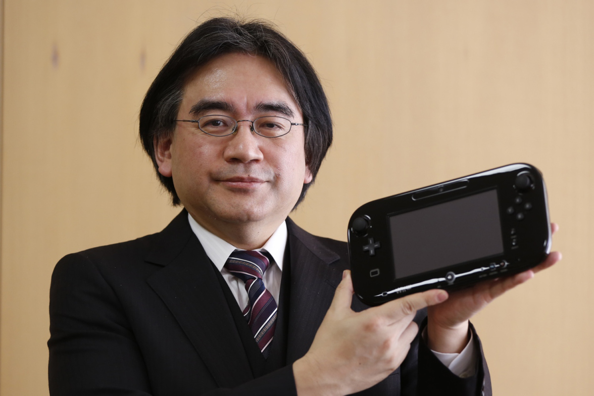 Nintendo Co's President Iwata poses with company's Wii U gaming controller at company headquarters after an interview with Reuters in Kyoto