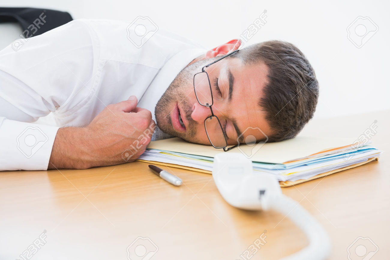 Exhausted businessman sleeping at his desk in his office