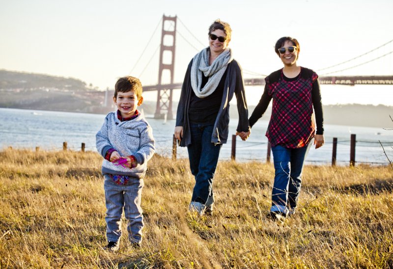 Un bambino passeggia felice con le sue due mamme Un bambino passeggia felice con le sue due mamme