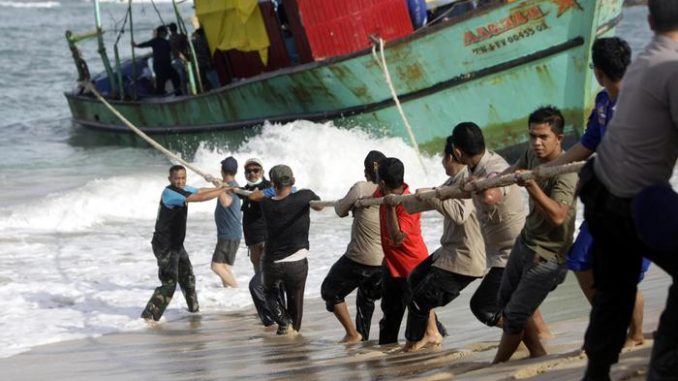 Un gruppo di migranti traina una barca a riva Un gruppo di migranti traina una barca a riva