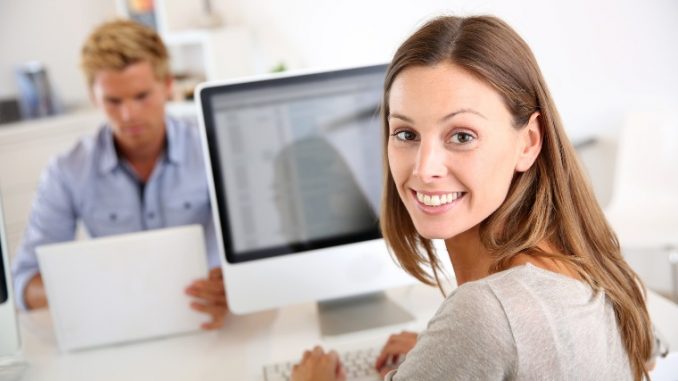 Portrait of smiling office worker in front of desktop