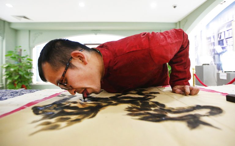Folk artist Han demonstrates painting with his tongue in Hangzhou