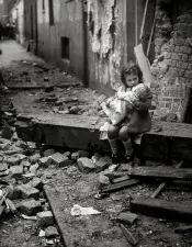 Una bambina con la sua bambola siede sulle macerie della propria casa bombardata Londra 1940