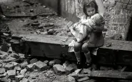 Una bambina con la sua bambola siede sulle macerie della propria casa bombardata Londra 1940