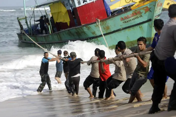 Un gruppo di migranti traina una barca a riva