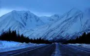 Una strada innevata di fronte alle montagne dellAlaska.