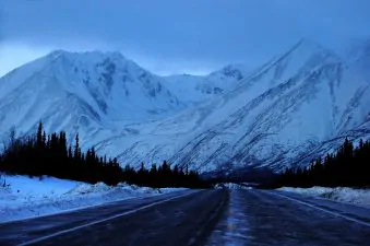 Una strada innevata di fronte alle montagne dellAlaska.