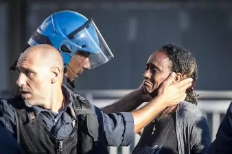 Un poliziotto conforta migrante sgomberata