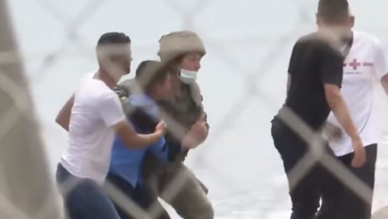 Un migrante aiutato da un soldato a Ceuta