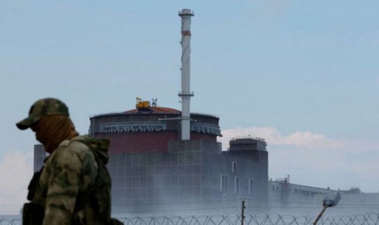 Un incursore russo e, sullo sfondo, la centrale di Zaporizhzhia