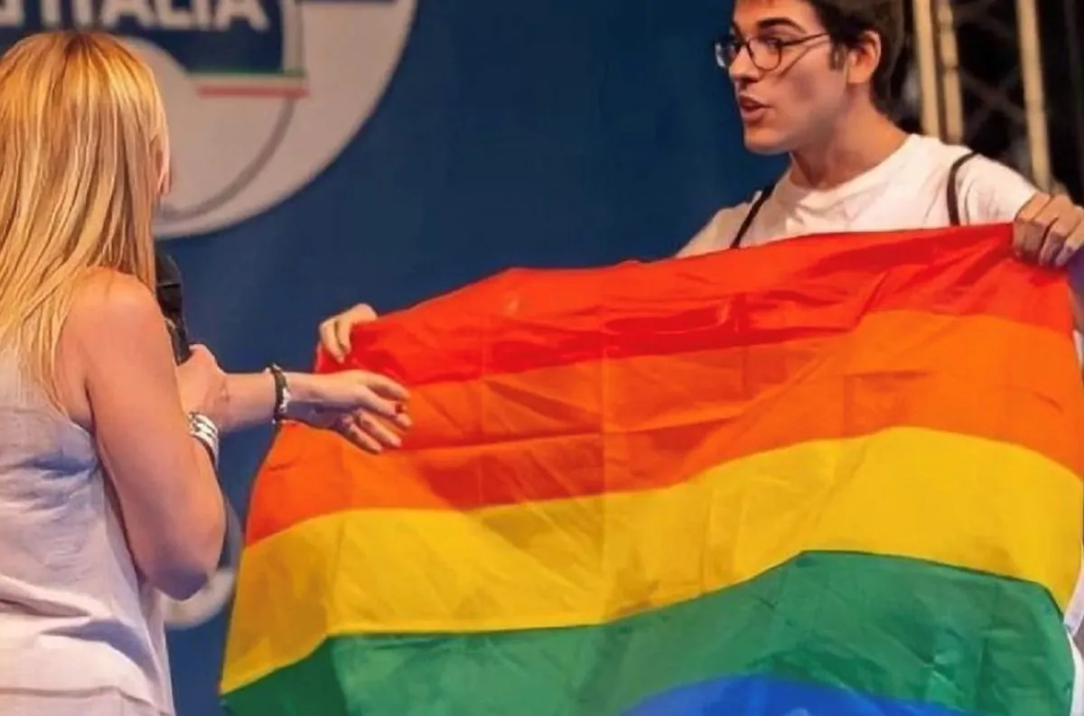Marco Marras sul palco con la Meloni e la bandiera arcobaleno