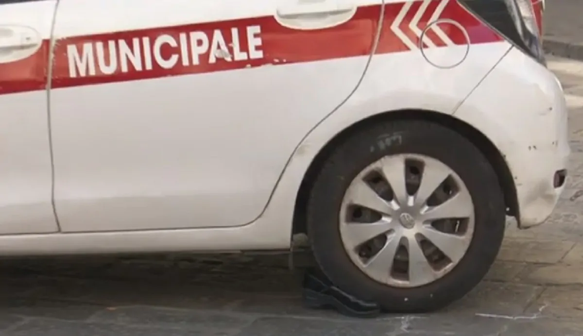 L'auto della municipale con una scarpa sotto la ruota in una ripresa Rai