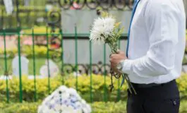 Funerale, uomo che porta i fiori alla tomba
